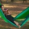 hamac mexicain XL en nylon, vert, vue de face avec une femme couché dans la diagonale qui lit un livre