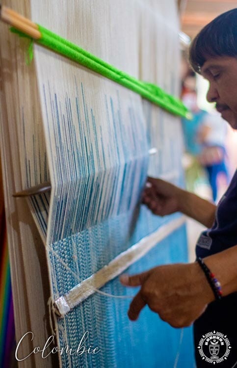 artisan Colombien qui tisse à la main un hamac sur un métier à tisser, vue de profil