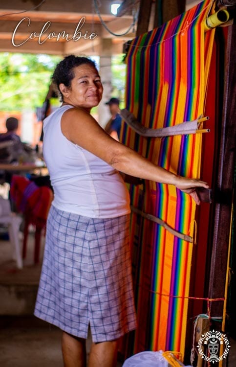tisserande de Colombie qui tisse un hamac multicolore sur un métier à tissé en fer, vue de coté