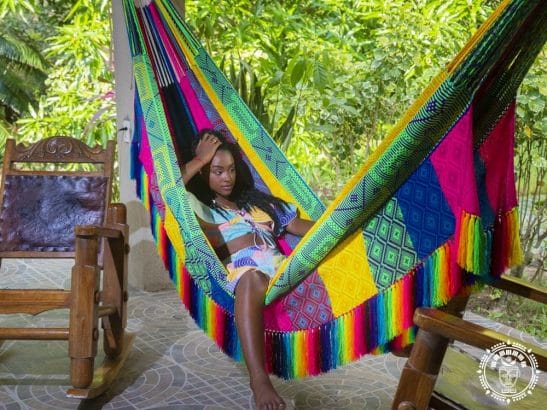 hamac XXL Premium de Colombie multicolore rose vert bleu et jaune. Photo de coté , vue de prés avec une femme qui se repose dans le hamac