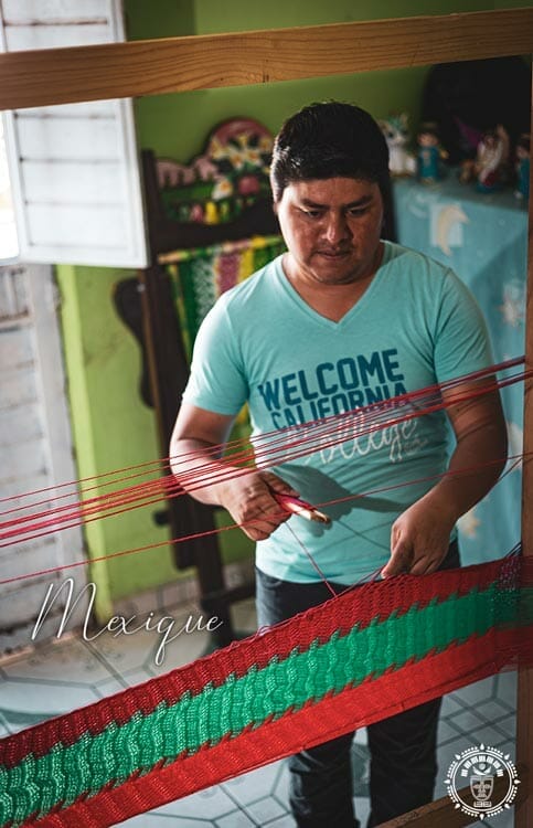 tisserand Mexicain qui tisse un hamac rouge et vert dans sa maison