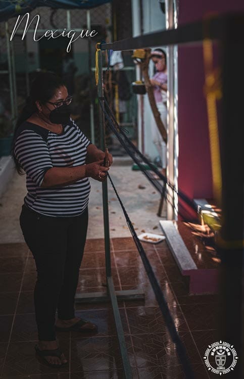 Une tisserande mexicaine qui tisse un hamac sur un métier à tissé, vue de profil
