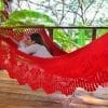 hamac à barre de luxe du Nicaragua en coton L, couleur rouge vu de coté, avec une femme sur le ventre allongée