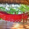 hamac à barre de luxe du Nicaragua en coton L, couleur rouge vu de coté, au dessus d'une terrasse en bois