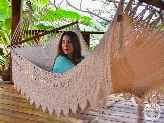 hamac à barre de luxe du Nicaragua vue de coté, gros plan sur les franges avec une femme à l'intérieur