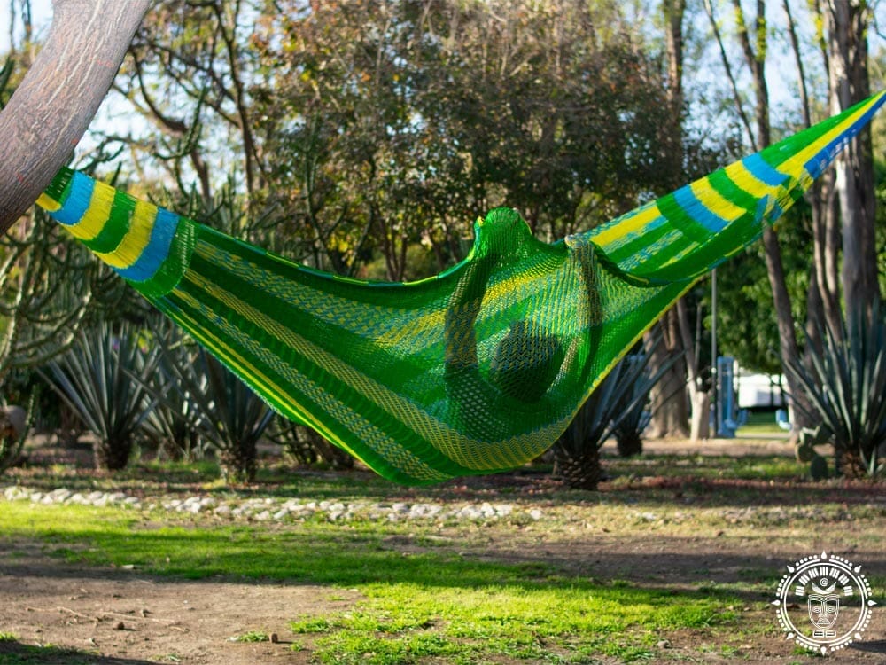 Hamac mexicain XXL vert, bleu et jaune avec un homme couché dans la largeur