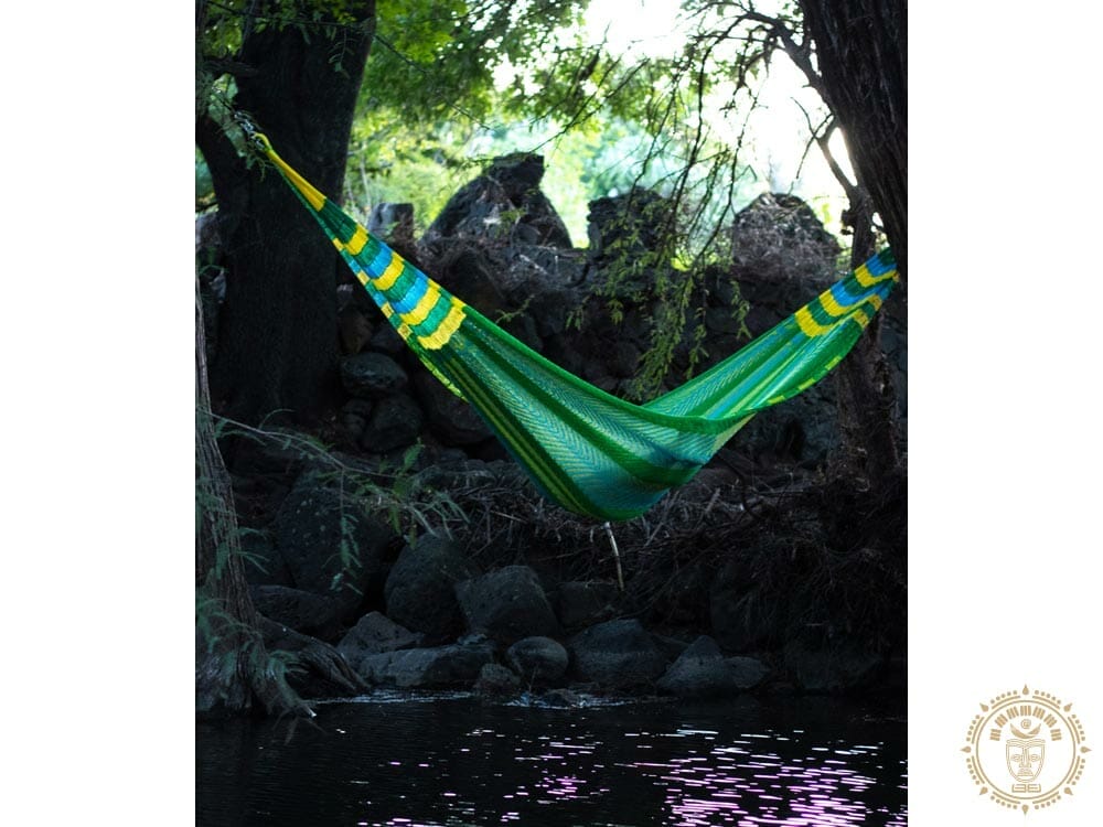 hamac XXL Mexicain vert, jaune et bleu avec une femme couché. en largeur sur une rivière