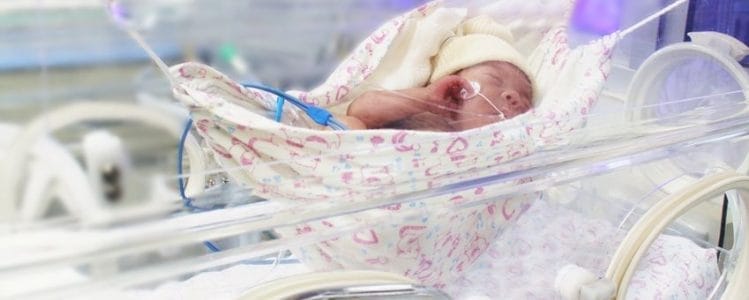 photo d'un bébé dans un petit hamac à l'intérieur d'une couveuse à l'hôpital. 
